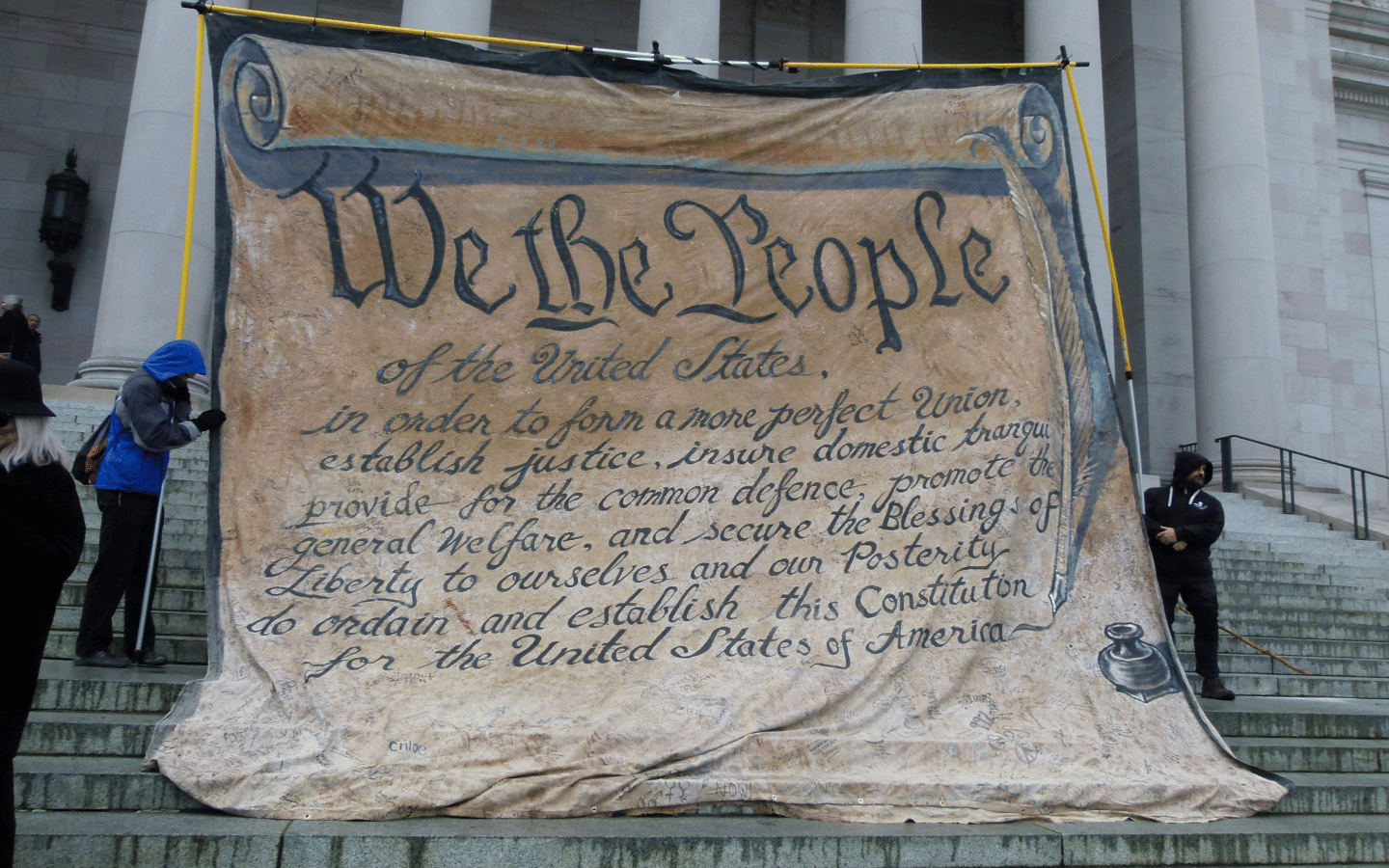 People unfurl a “We the People” banner on the steps of the U.S. Supreme Court.